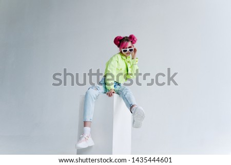 woman with pink hair sits on a cube on a light background
