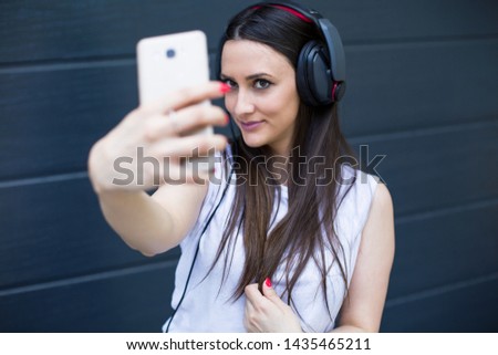 Happy young woman taking selfie outdoors - Stock image