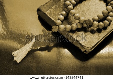 The holy bible and rosary beads on wooden background