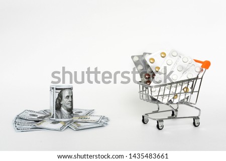Dollars, pills and shopping cart on a white background. Pharmacy concept. Copy space.