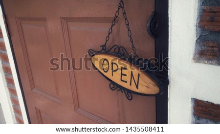 Wooden door of a shop with vintage "OPEN" sign hanging from the door knob