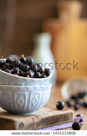 Blackcurrants stacked in a pale blue bowl in rustic kitchen