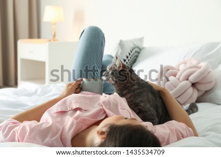 Young woman with cute cat on bed at home. Pet and owner