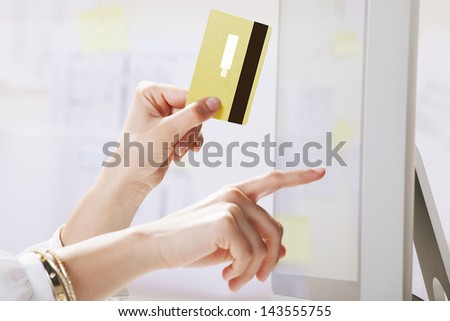 Young woman making payments online. / Young businesswoman with a credit card and pointing on the screen.