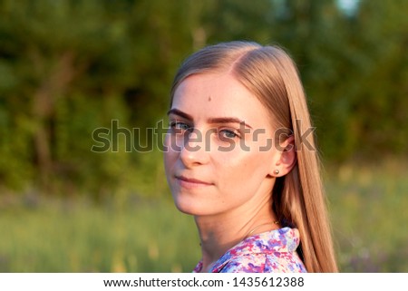 A happy young girl on a flowering field at sunset