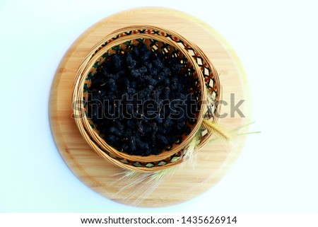 Dried black mulberries in straw basket  on white background Royalty-Free Stock Photo #1435626914