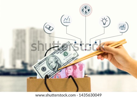The hand of female holds the chopsticks, which clamp yuan and the dollar banknote out of the paper bag.The concept of business growth, financial or trade economy.