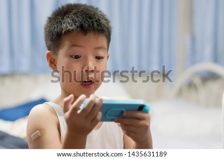 asian chinese boy playing smartphone on bed, watching smartphone, kid use phone and play game, child use mobile, addicted game and cartoon,