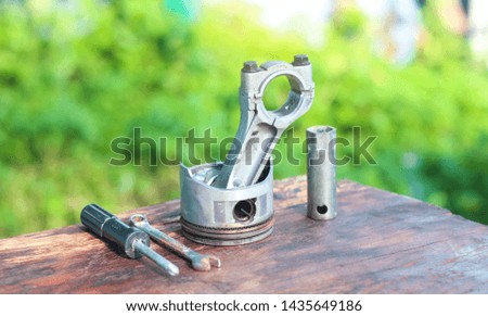Car piston and Mechanic tools on wood table background.