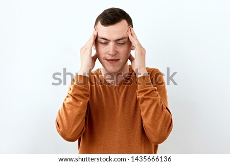 Keep balance. Calm and rest. Young man in orange sweater do atnti stress head massage , portrait against white background