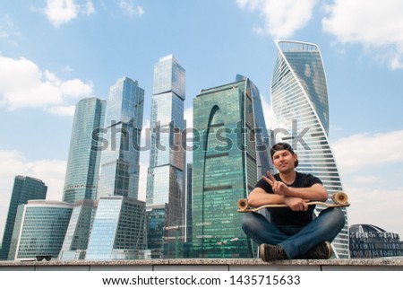 Skater on the background of a skyscraper, a guy with a longboard,
