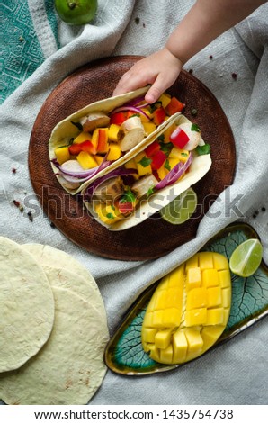 Mexican food tacos, fried chicken, salsa. greens, mango, avocado, pepper, red cabbage in tortillas