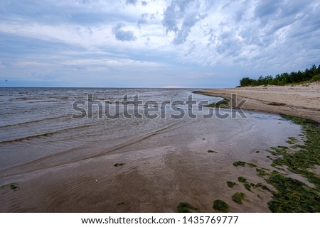 dramatic colorful clouds over sandy beach at the sea with blue sky and calm water in summer evening