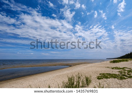 dramatic colorful clouds over sandy beach at the sea with blue sky and calm water in summer evening