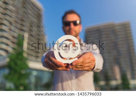 Businessman holding email symbol in front of business buildings. Contact us concept.