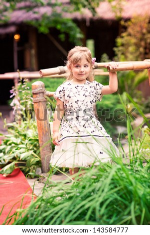 Charming little girl in a beautiful dress in a park outdoor