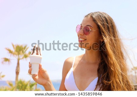 Girl eating ice cream on Tenerife beach with palm trees on the background