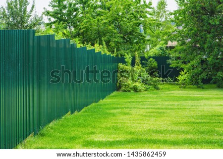 Landscape design of a gardening site. Fenced backyard with lawn and flower bed.