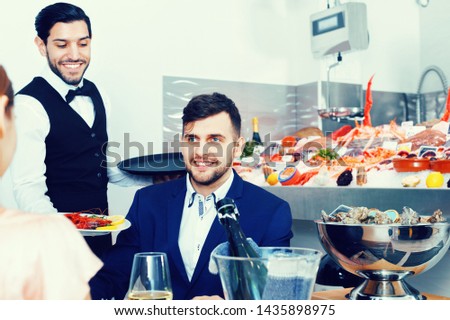 Portrait of young cheerful positive smiling man having good time with girl in fish restaurant