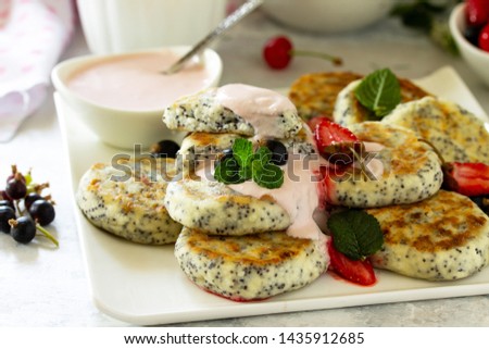 Summer breakfast background close-up. Homemade cottage cheese pancakes with poppy seeds, served sour cream sauce with strawberries. 