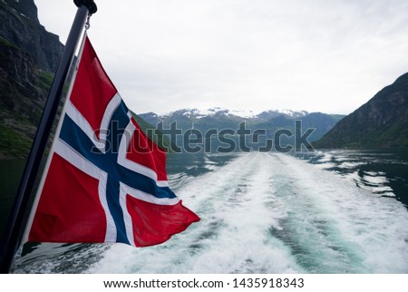 Cruise in Geiranger fjord. The flag of Norway.  Red with an indigo blue Scandinavian cross fimbriated in white that extends to the edges of the flag; the vertical part of the cross is shifted.