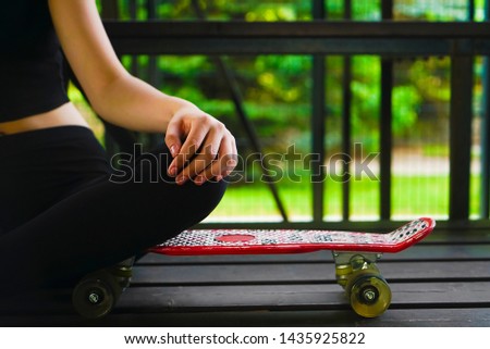 body of  slim girl . Young beautiful female  sitting on a red skateboard. Alternative lifestyle concept. girl sitting on short skate board