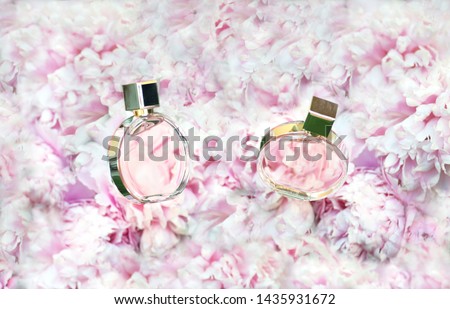 Rotating Perfume bottles on pink flowers peonies background - copy space. Perfumery, cosmetics, female accessories, fragrance collection. Delicate Perfume Bottle. two glass bottles of Chanel perfume