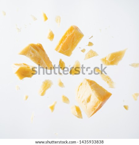 Parmesan cheese flying in different directions with crumbs on a white background with space for the text.  Royalty-Free Stock Photo #1435933838