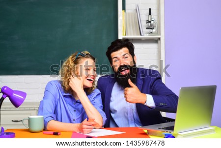 Portrait of two creative students in classroom. Student and tutoring education concept. Young female teacher with male student over green chalkboard background. Students couple studying in university.