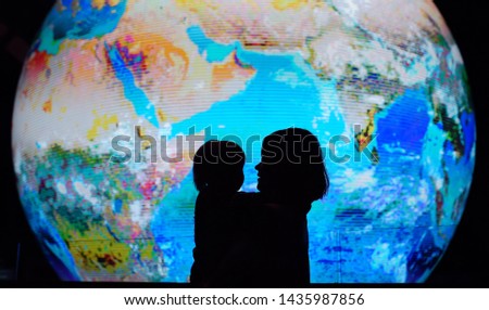 Silhouette of adult and child on background of globe earth. Ecologic and protection environment concept.
