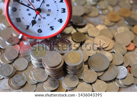 Close-up of many Thai  coins on wooden floors, antique alarm clocks placed near selective focus and shallow depth of field