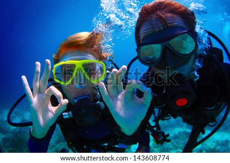 Underwater shoot of a couple diving with scuba and showing ok signal