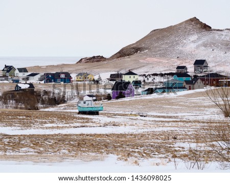 Traditional colored wooden houses in a snowy landscape, hill in background, Magdalen islands, Quebec, Canada