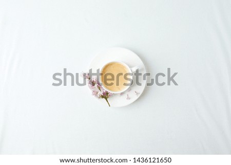 Morning breakfast with coffee cup and lilac branches on white background. Flat lay, top view women background. Minimal concept, wedding, valentine day