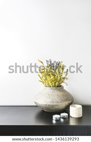 Interior design of room, mock-up, vase and lavender and lemon grass herbs bouquet, candles, white books on black table and white wall. Minimalism style.