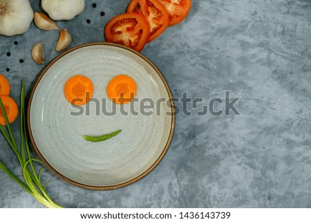 Emotion food happy on plate. Two carrot for eyes and green spicy chili for mouth. Smiley emotion made from vegetables. Food art concept. Lovely. Free space for any text design.