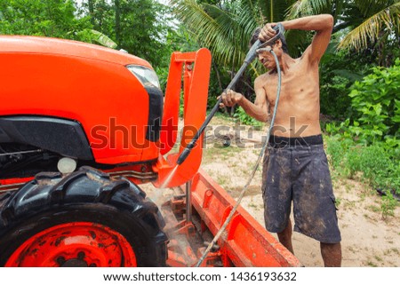 Asian farmers Using high pressure washer to clean a tractor. Back to work on the farm.
