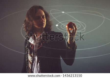 Physics the science of nature, the concept of studying the laws of nature. A young man in the image of Isaac Newton. With an Apple in hand, the concept of the laws of gravity. Royalty-Free Stock Photo #1436213150