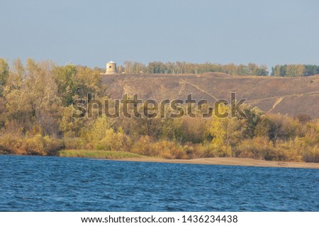 Autumn landscape, river, windy weather, dark blue water, yellow-red autumn leaves on trees, last warm days