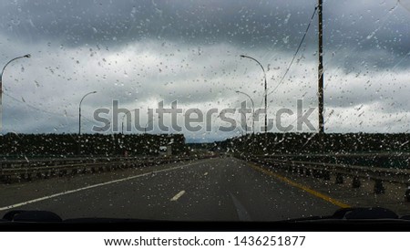 Raindrops on the windshield of the machine. View from the inside on the highway