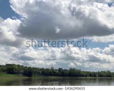 Blue beautiful sky against the background of the river. Clouds are displayed in calm water. On the horizon, the green bank of the Dniester. Picture taken from the middle of the river - image