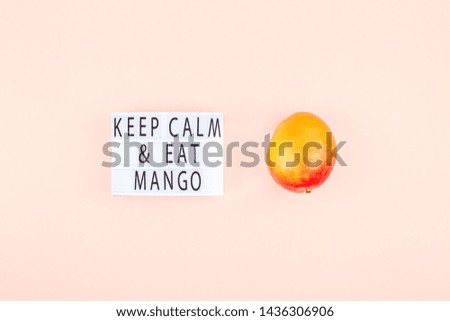 Mango fruit in creative conceptual top view flat lay composition with lightbox with Keep calm and eat mango slogan isolated on pink background in minimal style with copy space. Pop art concept poster
