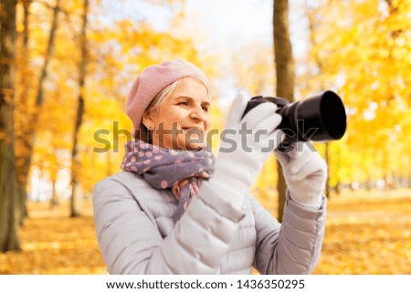 old age, retirement and people concept - happy senior woman with camera photographing at autumn park