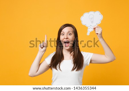 Excited young woman in casual clothes holding say cloud with lightbulb, pointing index finger up with great new idea isolated on yellow orange background. People lifestyle concept. Mock up copy space