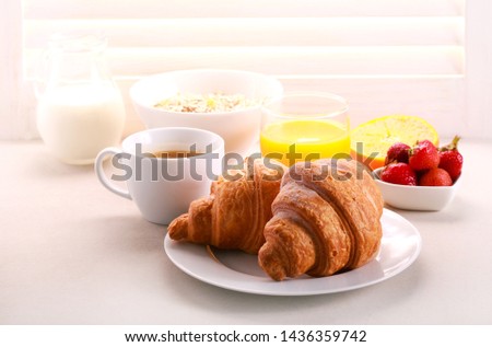 Breakfast with croissant, orange juice, and coffee served near the window