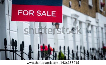 Estate agent ‘for sale’ sign on attractive row of terraced houses