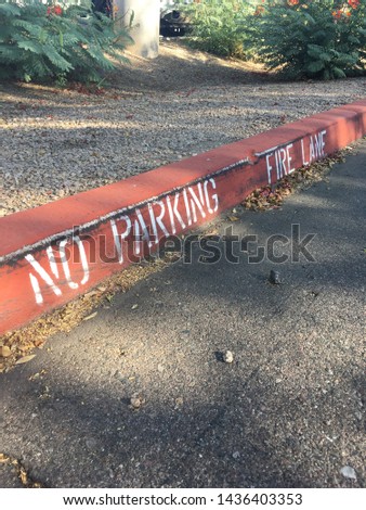 Red painted curb with message saying “no parking fire lane”