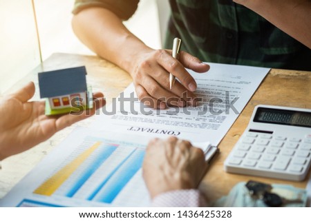 Estate agent pointing finger on document showing total cost. Signing a paper document for buying house.Real estate, home loan and insurance concept.