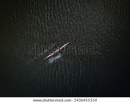 Aerial drone shot af academic rowing team in canoe on dark river