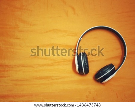 White wireless headphones placed on the orange floor